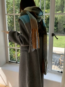 Detailed view of heavy rainbow check pattern scarf with tassels worn on shoulders