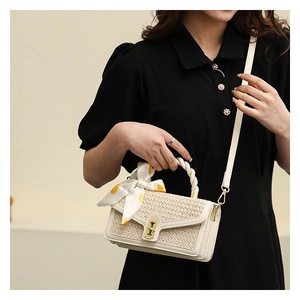 Detailed close-up of straw woven bag featuring a yellow dotted scarf and gold hardware
