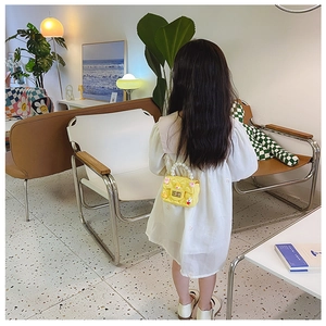 Rear view of child wearing a yellow quilted crossbody bag with pearl handle decor