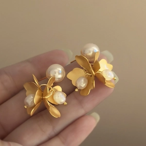 Close-up of vintage golden flower earrings with layered petals and glossy pearls