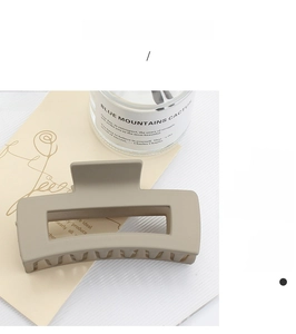 Close-up of a large matte khaki square hair claw clip on a minimalist textured surface