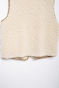 Detail of off-white fleece vest with brown trim and side slit hem on white background