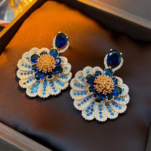 Close-up of vintage flower earrings with blue teardrop stones and orange zircon accents