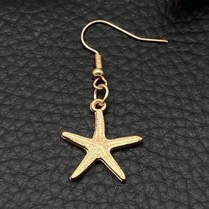 Close-up of golden starfish charm earring with detailed texture on black leather