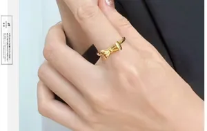 Close-up of golden bow-knot titanium ring on finger with refined ribbon texture