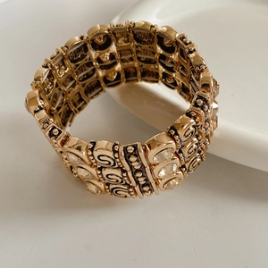 Detail of vintage gold-tone elastic bracelet with spiral patterns and crystal inlays