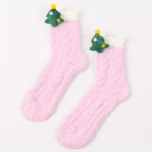 Detail von flauschigen rosa Korallenfleece-Socken mit weißem Rand und grünem Weihnachtsbaum