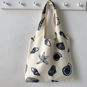 Detailed texture of canvas tote bag featuring navy blue starfish and shell patterns