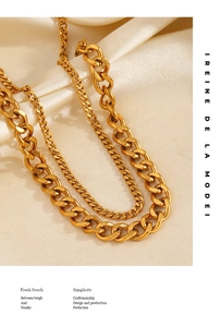 Detail view of double-layered gold Cuban link anklet on elegant beige silk fabric