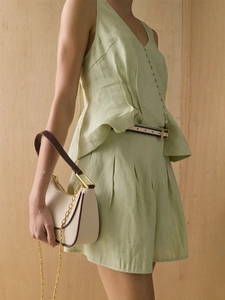 Detail of light green pleated cotton vest with fabric buttons and high waist A-line shorts