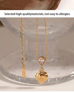 Detail of a golden strawberry pendant with zircon teardrop hanging on a glass rim