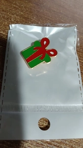 Vue détaillée d'une broche de Noël en émail en forme de cadeau rouge et vert doré