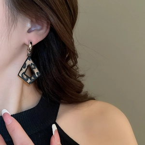 Gros plan d'un mannequin portant des boucles d'oreilles losanges en motif léopard chic