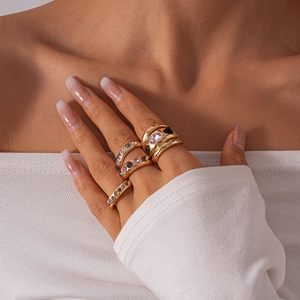 Detail of chunky gold stacking rings with pink and purple crystals on model's hand