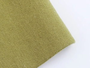 Macro shot of grass green linen fabric texture showing high-quality woven fiber details