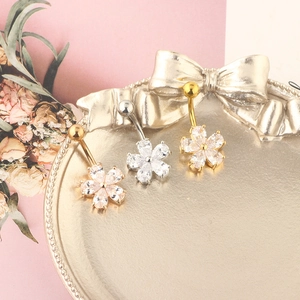 Three-color floral navel rings with petal zircons displayed on a gold vintage tray