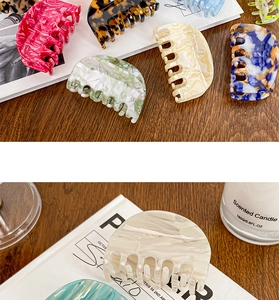 Detailed collection of assorted acetate hair claws on a rustic wooden table setting