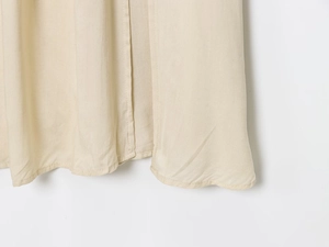 Gros plan détaillé de l'ourlet de la robe midi en coton beige avec des coutures doubles