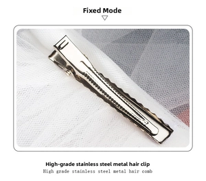Detailed close-up of a silver stainless steel hair clip with anti-slip teeth on white mesh