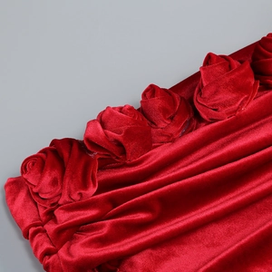 Detail of red velvet fabric featuring handcrafted 3D rose pleated decorations on the dress