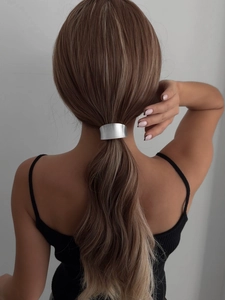 Silver bow hair cuff accessory shown on model securing a sleek low ponytail style