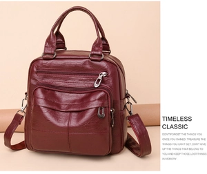 Detail view of burgundy leather backpack with multi-zipper pockets and top handle