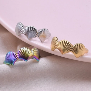 Macro view of shell-shaped stainless steel rings in gold, silver, and iridescent finishes