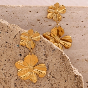 Detailed view of 18K gold plated double flower earrings on a natural stone base