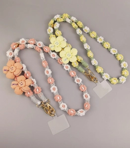 Macro detail of braided cotton phone lanyards with orange and yellow woven flower smiles