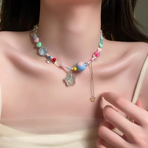 Close-up of a colorful beaded necklace with star and heart pendants on a model's neck