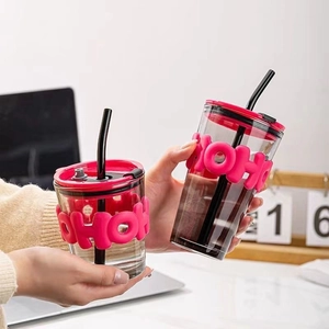 Close-up of glass coffee cup with pink HOHO silicone sleeve and red leak-proof lid