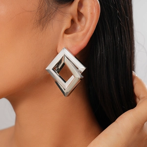 Close-up of geometric silver rhombus earrings on a model showing metallic luster