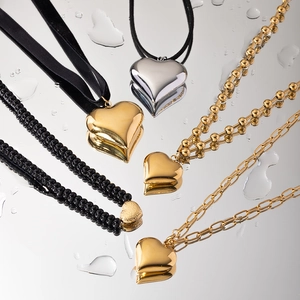 Classic heart necklace collection in gold, silver and black on a mirrored surface
