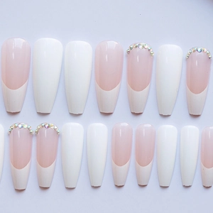 Detail of long ballerina press-on nails with white French tips and crystal rhinestones