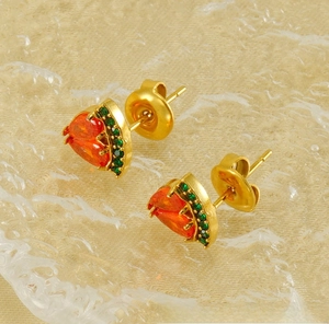 Détail macro d'une boucle d'oreille pastèque avec zircon orange et pierres vertes sur l'eau