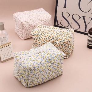 Quilted floral cosmetic bags in pink, yellow, and blue with zipper closure on a desk
