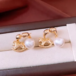 Vintage style gold rocking horse pearl stud earrings displayed in a luxury jewelry box