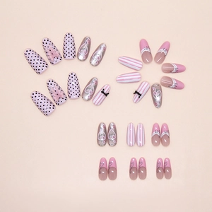 Detail of pink French cat-eye press-on nails with bow, vine, and polka dot designs