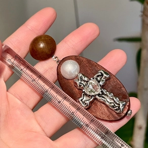 Détail des boucles d'oreilles croix en bois avec cœur cristal et règle de mesure