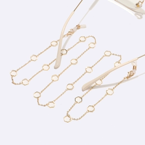 Close-up of golden metal eyeglass chain featuring elegant cream-white hexagonal charms