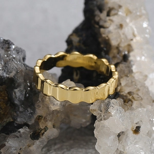 Detailed view of a gold-plated scalloped wave ring resting on a natural stone background