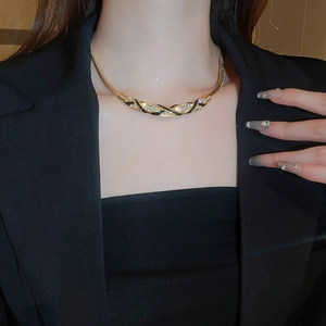Close-up of vintage gold curved necklace with black enamel and diamonds on a model