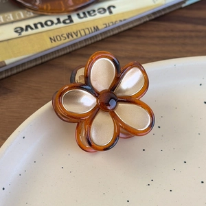 Macro view of amber floral hair claw clip on a ceramic tray with aesthetic styling