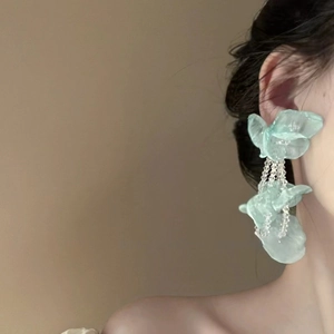 Détail de boucles d'oreilles fleurs bleues aux pétales translucides et gland perlé