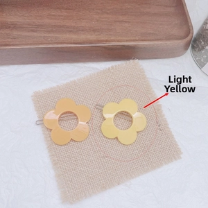Detail of colorful resin flower hair clips in light yellow and amber on a linen background