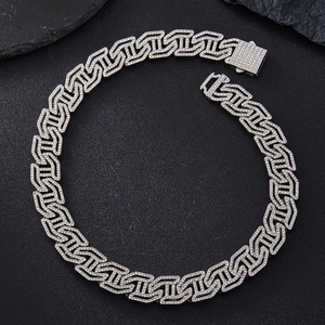 Detailed view of a silver Cuban link necklace with iced-out rhinestones on black stone