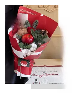 Close-up of Christmas bouquet with teddy bear, red rose, and pine cones in festive wrap