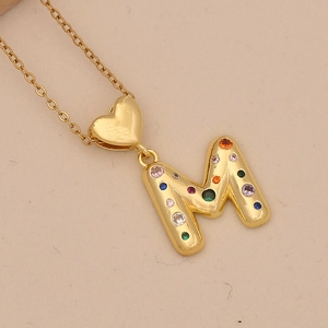 Macro detail of golden M letter pendant with multi-color zircon stones and heart charm