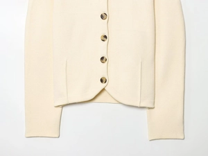 Detail of beige knit cardigan hem featuring brown tortoiseshell buttons and soft texture