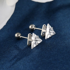 Detailed close-up of triangle cut zircon stud earrings with screw ball backings on blue velvet